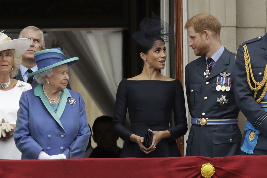 FILE - In this Tuesday, July 10, 2018 file photo Britain's Queen Elizabeth II, Meghan the Duchess of Sussex and Prince Harry stand on a balcony to watch a flypast of Royal Air Force aircraft pass over ...