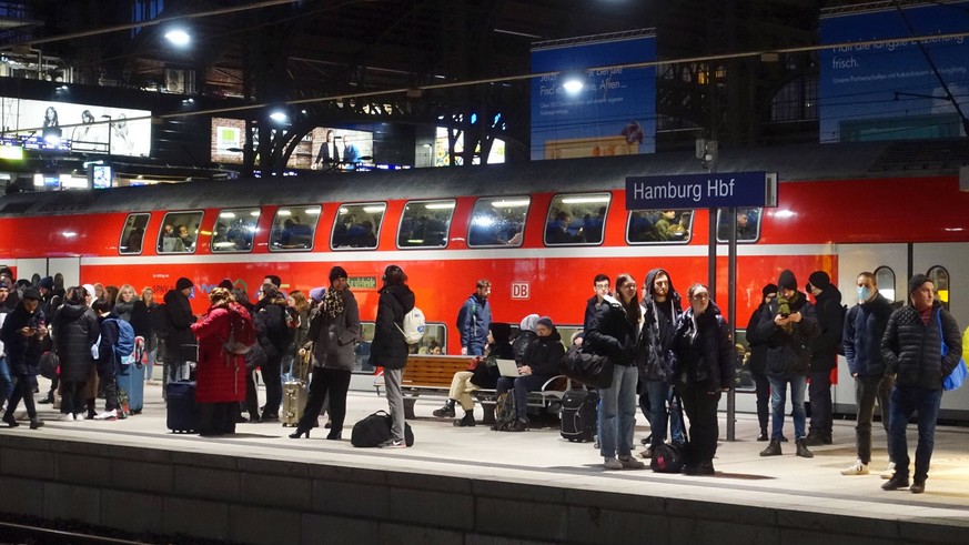 03.02.2023, Hamburg, Hansestadt Hamburg, GER - Reisende warten auf einem Bahnsteig im Hauptbahnhof auf den Zug. Abend, abends, Alltag, Bahn, Bahnhof, Bahnreise, Bahnreisende, Bahnstation, Bahnsteig, B ...