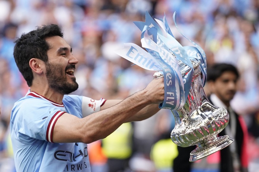 Manchester City&#039;s Ilkay Gundogan holds up the winners trophy as he celebrates winning the English FA Cup final soccer match between Manchester City and Manchester United at Wembley Stadium in Lon ...