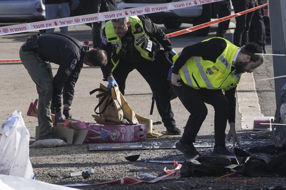 Members of Zaka Rescue and Recovery team and Israeli police forensics pick up a doll at the site of a car-ramming attack at a bus stop in Ramot, a Jewish settlement in east Jerusalem, Friday, Feb. 10, ...