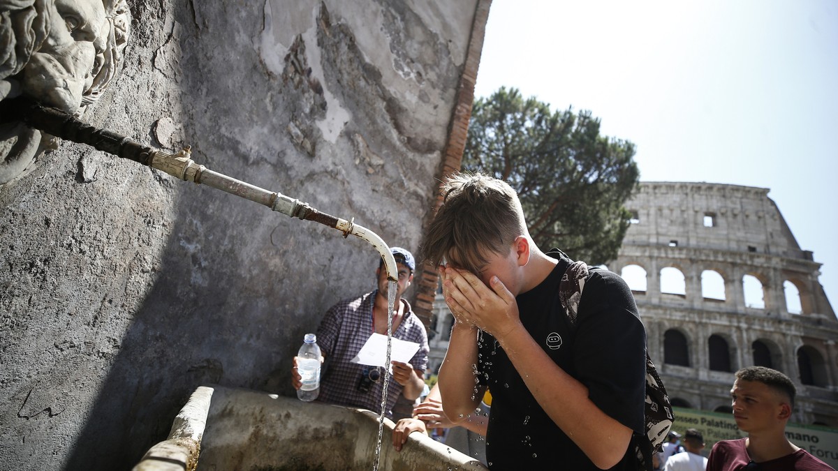 ARCHIV - 12.08.2021, Italien, Rom: Ein Junge erfrischt sich an einem Brunnen neben dem Kolosseum. Viele st