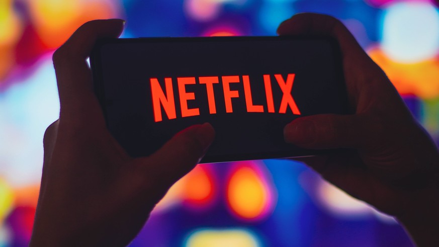 July 6, 2022, Brazil. In this photo illustration, a silhouetted woman holds a smartphone with the Netflix logo displayed on the screen. July 6, 2022, Brazil. In this photo illustration, a silhouetted  ...