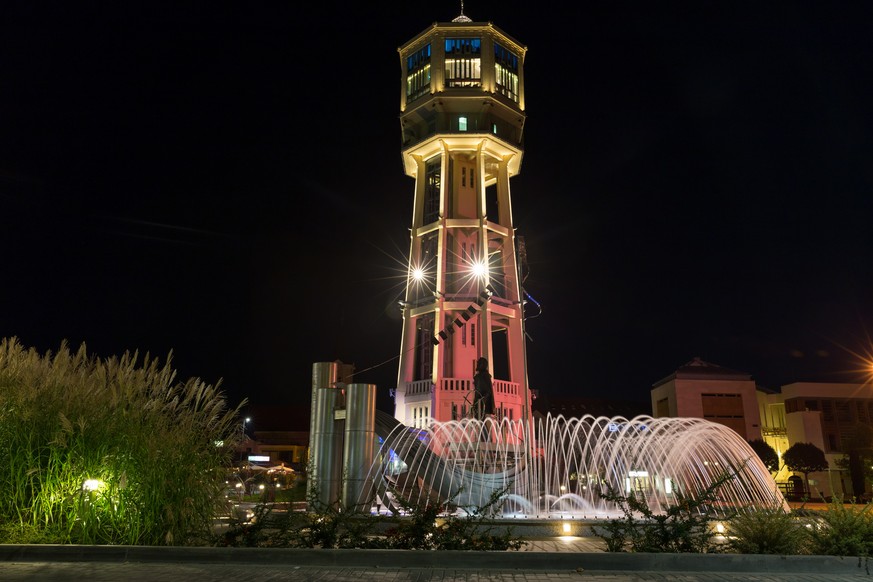 Siofok, Hungary - September 8, 2014: Old wooden water tower and fountain in square Siofok with night red illumination