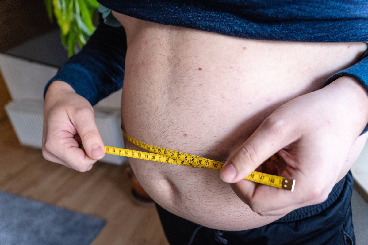 Augsburg, Bavaria, Germany - January 14, 2024: Symbolic image of overweight and obesity, a fat young man measures the circumference of his big belly *** Symbolbild �bergewicht und Fettleibigkeit, ein  ...