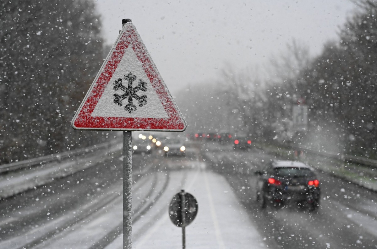 Schneefall in Ostfriesland. Das Verkehrszeichen 101-51 Schnee- oder Eisglätte warnt vor Glätte durch Vereisungen sowie Schnee auf der Straße. Mehrere Zentimeter Schnee sorgen für glatte Straßen in Lee ...