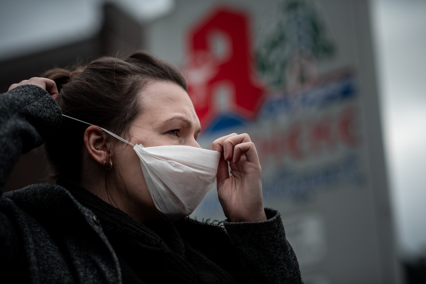 Eine Frau trägt vor einer Apotheke eine Mund- und Nasenmaske. Der erste Fall des Corona-Virus in Deutschland hat die Nachfrage nach Atemmasken in Apotheken stark erhöht.
