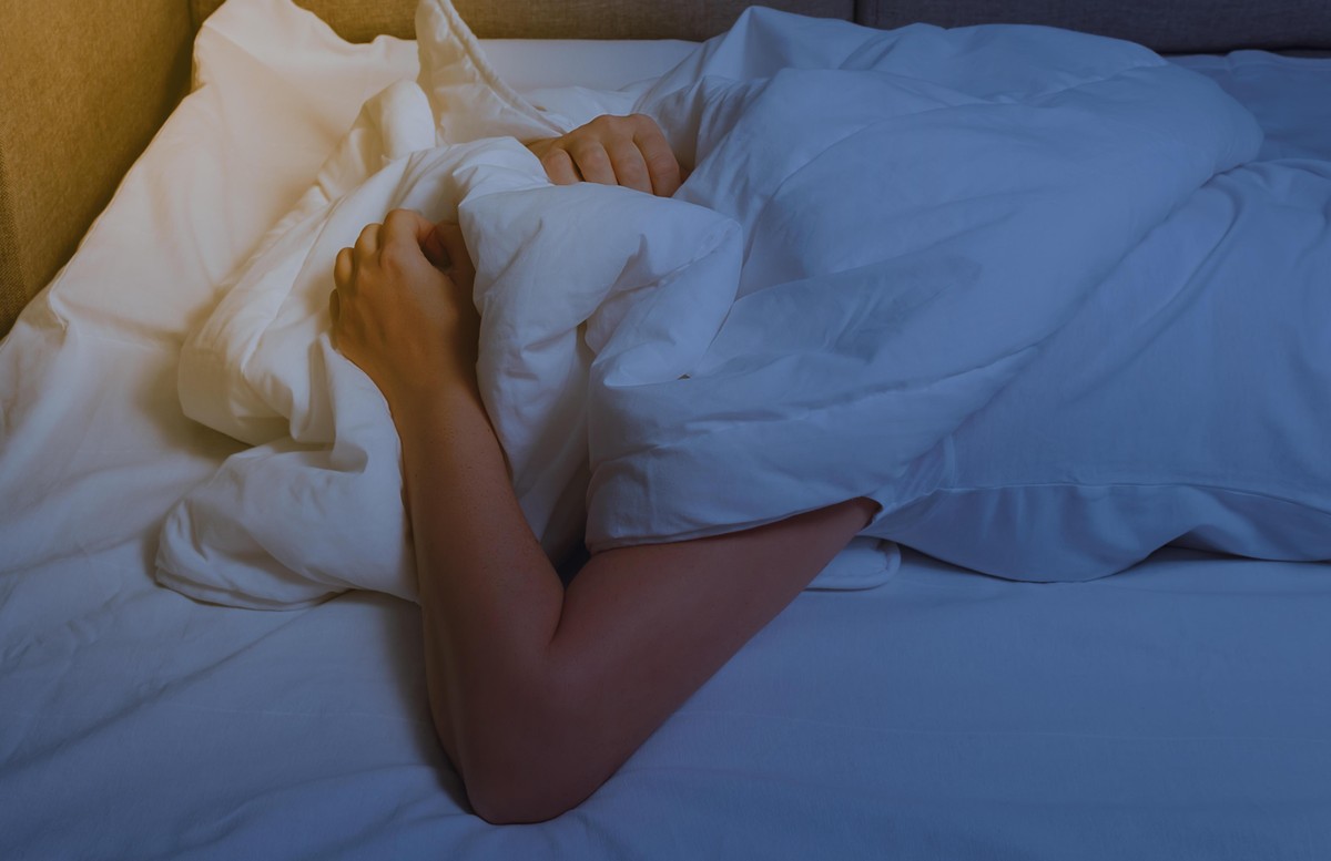 Woman's hands are visible from under the covers as a symbol of fight against insomnia. Tired and exhausted person has nightmares. || Modellfreigabe vorhanden