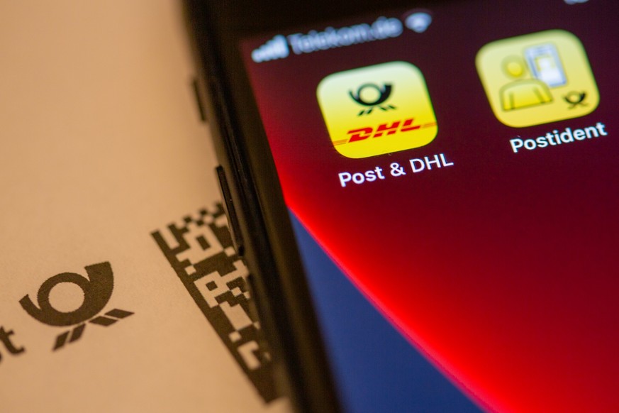 ARCHIV - 05.12.2021, Berlin: Das Logo der Post &amp; DHL App ist auf dem Display eines Smartphones zu sehen. Im Streit über die Gültigkeit sogenannter mobiler Briefmarken hat die Deutsche Post eine Ni ...