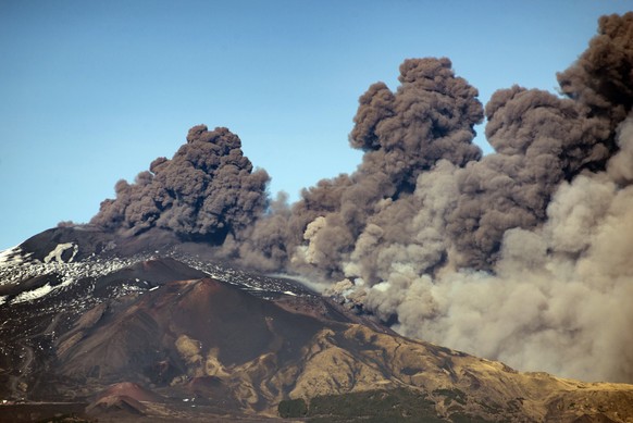 A smoke column comes out of the Etna volcano in Catania, Italy, Monday, Dec. 24, 2018. The Mount Etna observatory says lava and ash are spewing from a new fracture on the active Sicilian volcano amid  ...