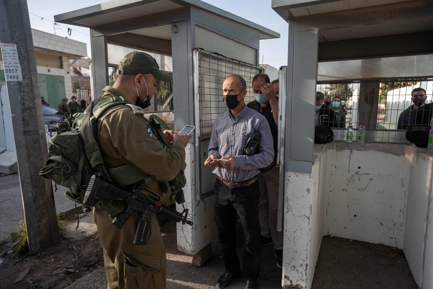210416 -- BETHLEHEM, April 16, 2021 -- An Israeli soldier checks the identity card of a Palestinian man who passes an Israeli checkpoint to attend the first Friday prayers of the fasting month of Rama ...
