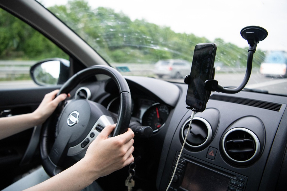 ARCHIV - 18.05.2022, Niedersachsen, Leer: Eine Frau sitzt im Auto mit einem Smartphone in einer Halterung. (zu dpa: