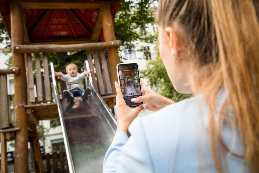 ILLUSTRATION - Eine Frau macht am 09.09.2020 in Berlin auf einem Spielplatz ein Foto von ihrem Sohn beim Spielen (gestellte Szene). Foto: Christin Klose