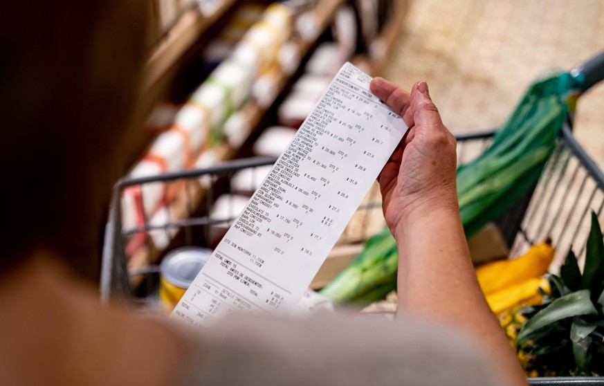 Close-up on a woman looking at a receipt after shopping at the supermarket - cost of living concepts