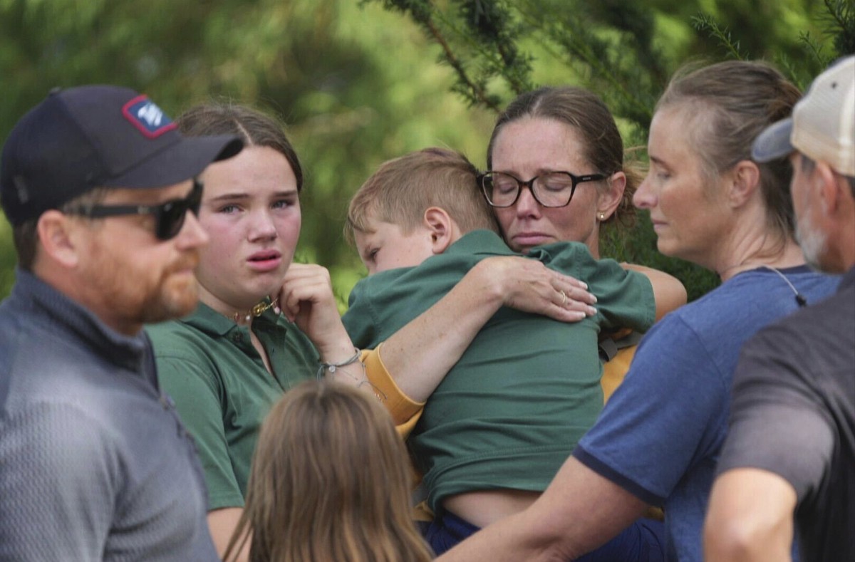 Parents comfort their children after a shooting at Annunciation Church on Wednesday, Aug. 27, 2025 in Minneapolis. (Alex Kormann/Star Tribune via AP)/