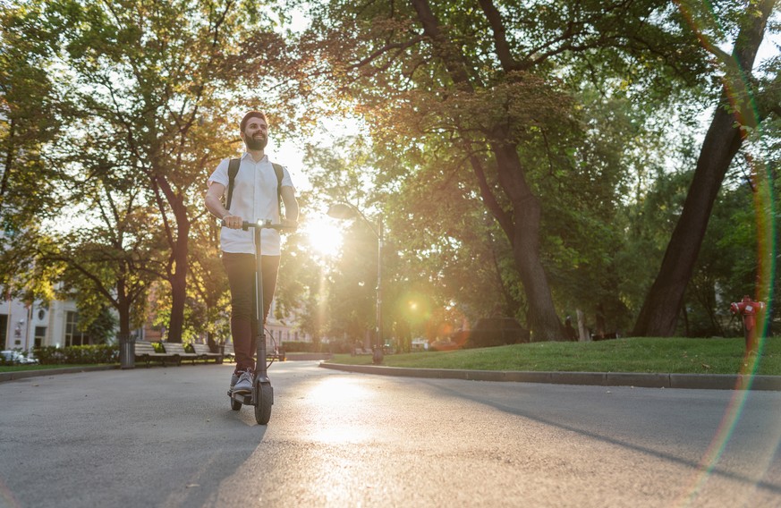 Young man riding his electric scooter in the city park