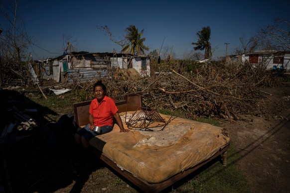 FILE - Mari Carmen Zambrano poses for a photo on her broken and wet bed as she dries it outside her home that lost its roof to Hurricane Ian in La Coloma, in the province of Pinar del Rio, Cuba, Wedne ...