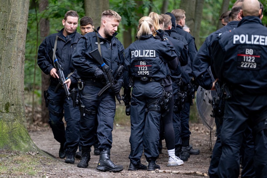 21.07.2023, Brandenburg, Kleinmachnow: Polizisten laufen im Bereich der südlichen Landesgrenze von Berlin. Ein gefährliches Wildtier soll in der Nacht zum Donnerstag in Brandenburg entlaufen sein und  ...