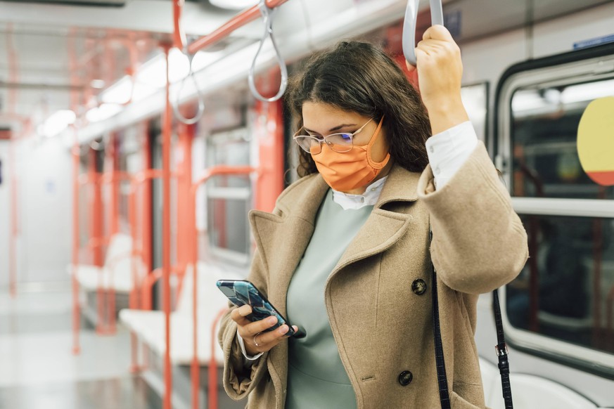 Curvy woman using mobile phone in train during pandemic model released, MEUF04844