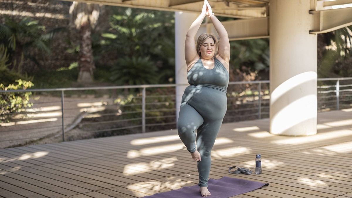 Young curvy woman practicing tree pose on mat in park model released, Symbolfoto, ALZF00060
