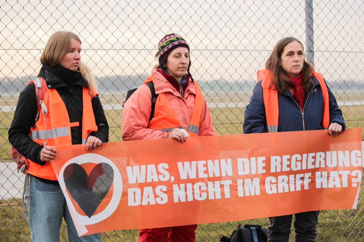 Letzte Generation demonstriert am Flughafen M�nchen Aktivist*innen der Letzten Generation demonstrierten am 8.12.2022 vor dem Stcheldrahtzaun des M�nchner Flughafens und auf dem Rollfeld f�r die Wiede ...