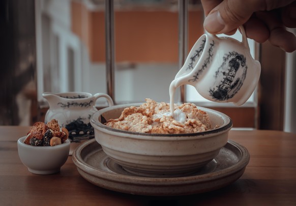 Pouring milk into the Cereal in Ceramic bowl served with Tasty Gadola on wooden table. Healthy breakfast concept, Space for text, Selective focus. Model Released Property Released xkwx almond appetize ...