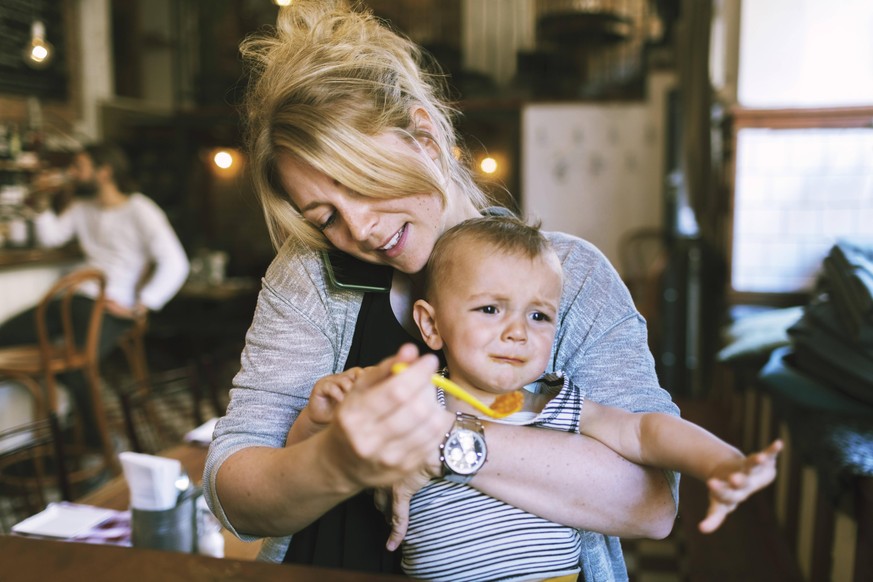 Mid adult mother trying to feed baby boy in restaurant , model released Copyright: xMaskotx , MA47180