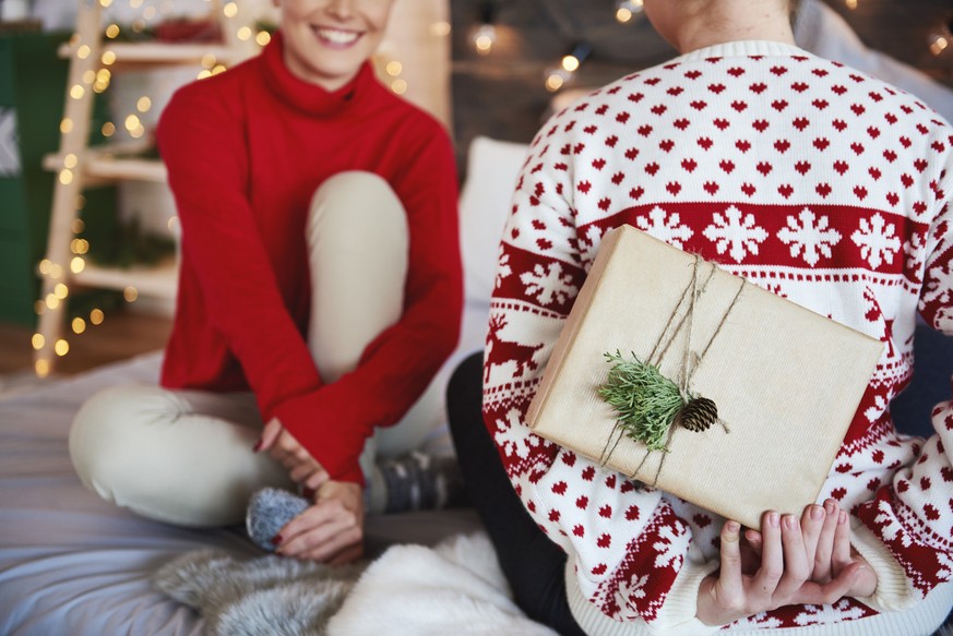 Rear view of woman giving christmas present her friend