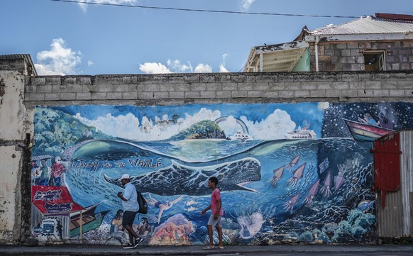 People walk past a mural of a whale created by artist Marcus Cuffi in Roseau, Dominica, Sunday, Nov. 12, 2023. The tiny island of Dominica announced on Nov. 13, 2023 that it is creating the world’s fi ...