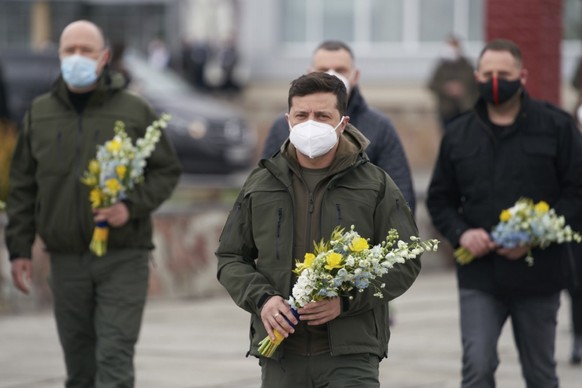 Ukrainian President Volodymyr Zelenskiy, center, in a face mask to protect against coronavirus, lay flowers at the monument to Chernobyl victims during a memorial ceremony in Chernobyl, Ukraine, Sunda ...