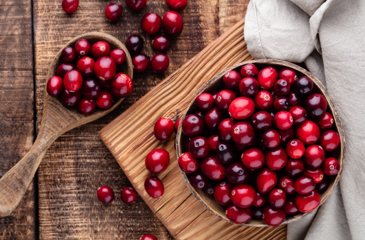 Ripe cranberry in wooden bowl on wooden table.