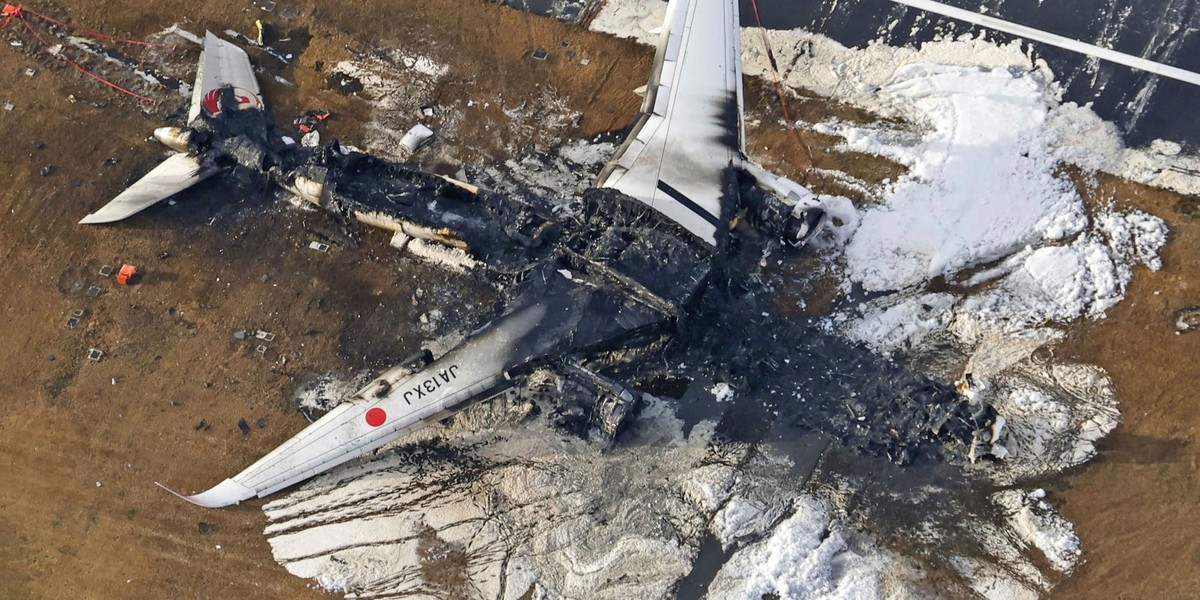 03.01.2024, Japan, Tokio: Die Luftaufnahme zeigt das ausgebrannte Flugzeug der Japan Airlines auf dem Flughafen Haneda. Ein Passagierflugzeug der Japan Airlines (JAL) stieß am Dienstag aus noch ungekl ...