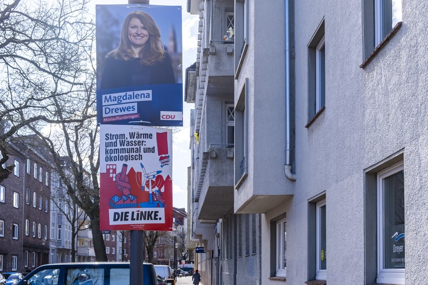 ARCHIV - 05.04.2023, Schleswig-Holstein, Kiel: Wahlplakate von CDU und der Partei Die Linke zur Kommunalwahl in Schleswig-Holstein hängen an einem Laternenmast. Am 14. Mai 2023 werden in Schleswig-Hol ...