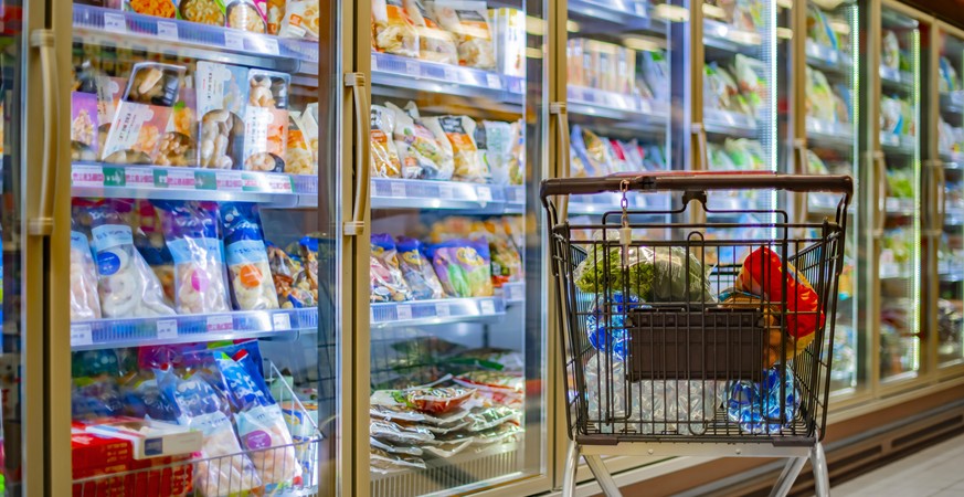 A shopping cart with grocery products in a supermarket