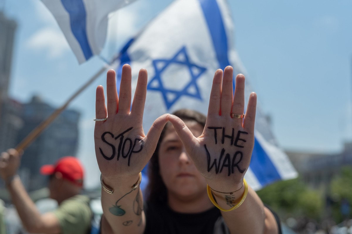 07.07.2024, Israel, Tel Aviv: Israelische Demonstranten rufen Slogans und halten israelische Flaggen, während sie sich zu einer Kundgebung versammeln, um den 9. Monat seit dem Hamas-Angriff am 07. Okt ...