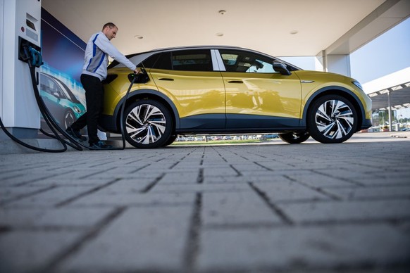 ZWICKAU, GERMANY - SEPTEMBER 18: A worker charges the new Volkswagen ID.4 electric sport utility vehicle (SUV) at the VW factory on September 18, 2020 in Zwickau, Germany. Volkswagen will officially p ...