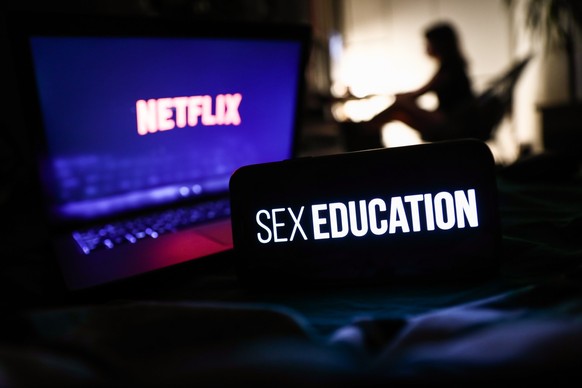 Sex Education series logo displayed on a phone screen, Netflix logo displayed on a laptop screen and a silhouette of a woman in the background are seen in this illustration photo taken in Krakow, Pola ...