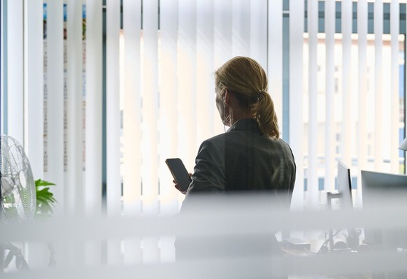 ARCHIV - 10.07.2021, Berlin: ILLUSTRATION - Eine Frau steht in einem Bürozimmer am Fenster und telefoniert über ein Headset (gestellte Szene). Auf der Tagesordnung des EU Parlaments steht unter andere ...