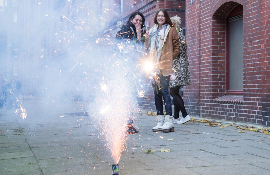 ILLUSTRATION - Drei junge Frauen stehen am 08.11.2017 vor einem Wohnhaus in Hamburg und schauen einem Bodenfeuerwerk zu (gestellte Szene). Foto: Christin Klose || Modellfreigabe vorhanden