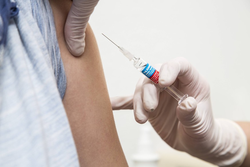 Arztpraxis, junge Frau bekommt eine Grippeschutz Impfung, Vaxigrip