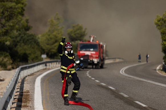 18.07.2023, Griechenland, Mandra: Ein Feuerwehrmann ist bei einem Waldbrand im Einsatz. Den dritten Tag in Folge haben Feuerwehrleute in Griechenland gegen drei gro�e Feuerfronten angek�mpft. F�r die  ...