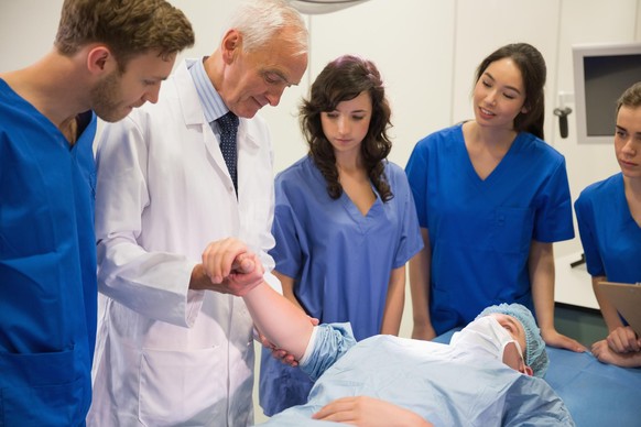 Medical students and professor checking pulse of student at the university