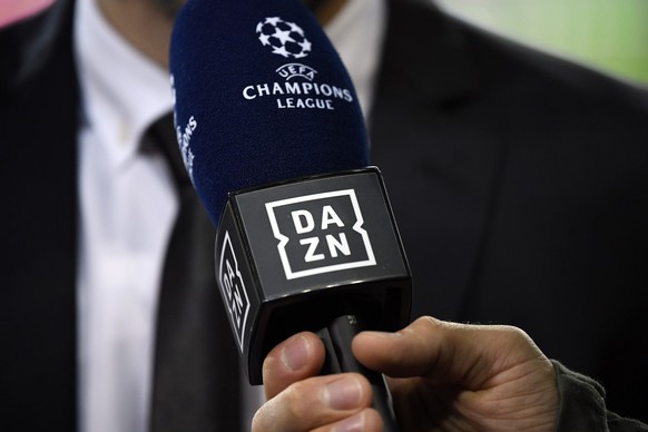 ARCHIV - 28.11.2018, Portugal, Porto: Ein Reporter hält ein Mikrofon des Streamingdienstes DAZN während eines Interviews fest. Der Internet-Anbieter DAZN hat sich das größte Rechtepaket an der Fußball ...
