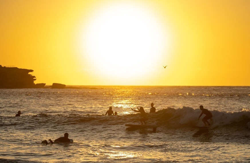 SYDNEY, AUSTRALIA - FEBRUARY 17: People surf at Bondi Beach early in the morning as the sun rises on February 17, 2023 in Sydney, Australia. Bondi Beach is the most popular beach in Australia with jus ...