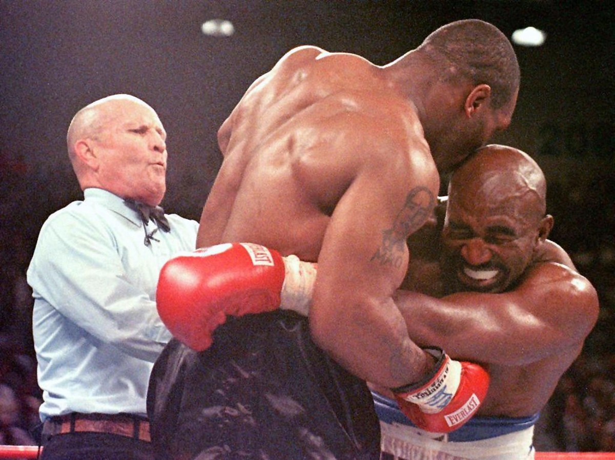 ARCHIV - 29.06.1997, USA, Las Vegas: Der damalige Weltmeister im Schwergewicht, Evander Holyfield (r), verzieht das Gesicht, nachdem ihn sein Herausforderer Mike Tyson (M) ins Ohr gebissen hat. (zu dp ...