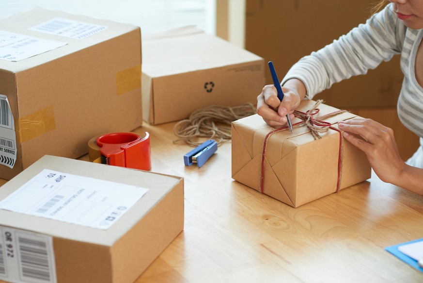 Cropped image of woman writing best wishes on box with present