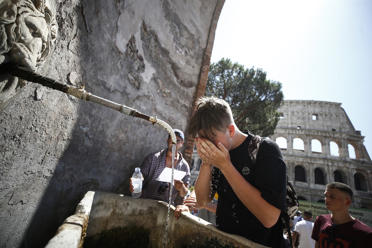 ARCHIV - 12.08.2021, Italien, Rom: Ein Junge erfrischt sich an einem Brunnen neben dem Kolosseum. Viele st