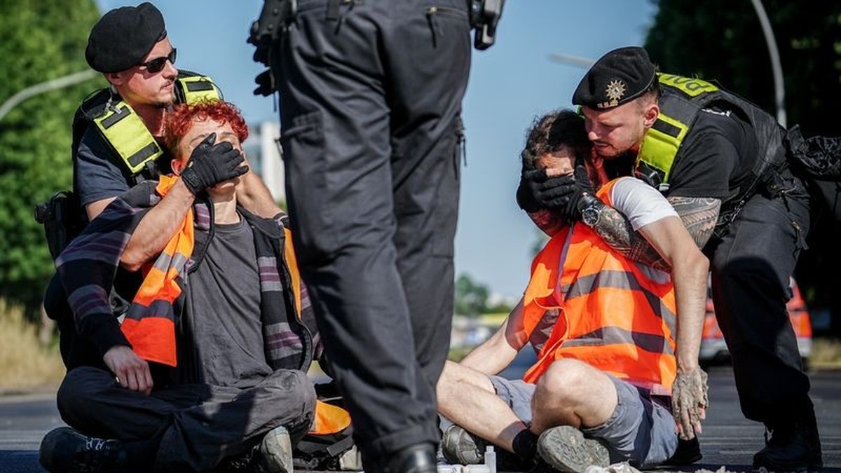 12.06.2023, Berlin: Aktivisten der Gruppe Letzte Generation werden bei einer Blockadeaktion am Großen Stern an der Siegessäule von der Polizei von der Straße entfernt. Sie klebten sich auf der Straße  ...