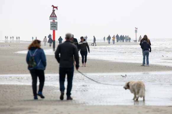 23.04.2023, Schleswig-Holstein, St. Peter-Ording: Passanten sind am Strand von St. Peter- Ording unterwegs. In St. Peter-Ording an der Nordsee ist am Freitag am Strand ein Wolf gesichtet worden. Ein M ...