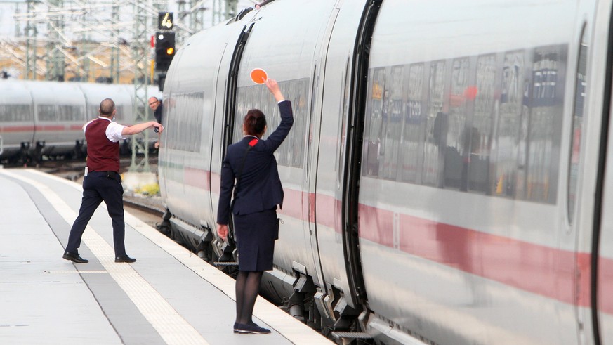 Zugbegleiter der DB Deutsche n Bahn AG signalisieren dem aus dem Fenster schauenden Lokf
