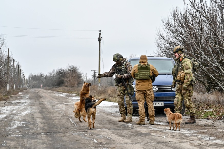 HULIAIPOLE, UKRAINE - JANUARY 14, 2023 - Ukrainian servicemen surrounded by dogs stay by a car parked on the roadside, Huliaipole, Zaporizhzhia Region, southeastern Ukraine. Russian troops attack Huli ...